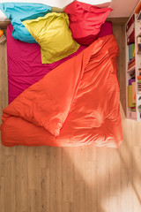 top view of an bed with a duvet and brightly colored pillows