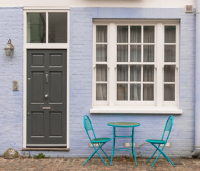 Fototapeta na wymiar Two blue metal chairs and table next to black door