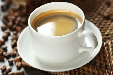Cup of coffee with beans on table close up