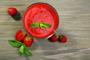 Glass of strawberry smoothie with berries on wooden table close up