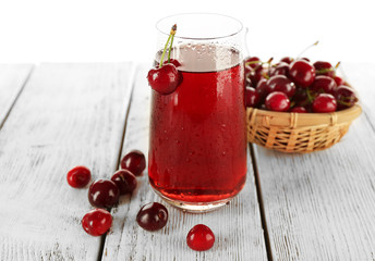 Glass of fresh juice with cherries on wooden table close up