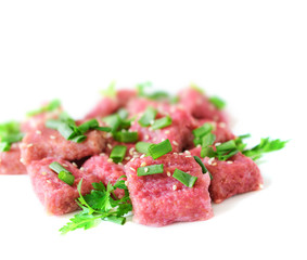 Gnocchi from beet with green onions and parsley on a white background.