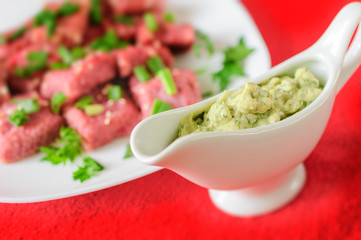 Green sauce in a sauce-boat and red gnocchi with beet and green onions.