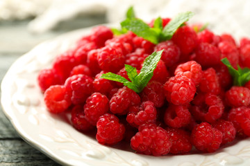 Sweet raspberries on plate on wooden  background