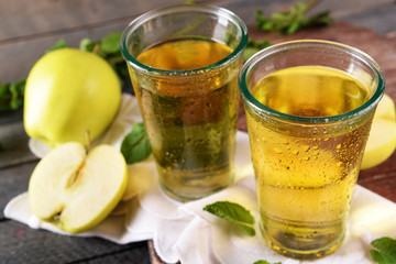 Wet glasses of apple juice on wooden table, closeup