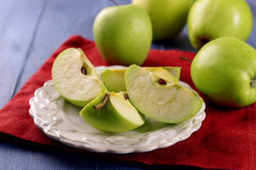 Pieces of green apple in saucer on wooden table with napkin, closeup