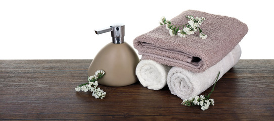 Soft towels with dispenser and flowers isolated on white