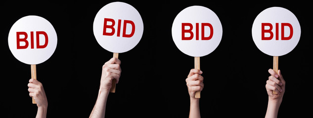 Bidders' hands lifting auction paddles

