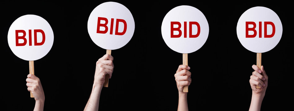 Bidders' hands lifting auction paddles
