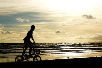 Children and bike silhouette on the sand beach.