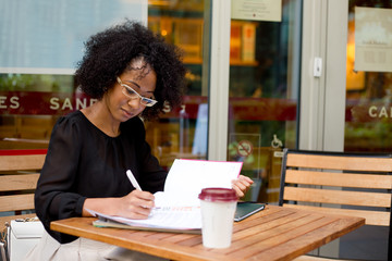 young woman at a coffee shop writing in her diary