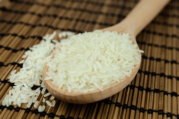 Rice in wooden spoon on traditional Asian plate mat