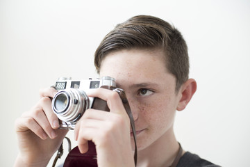 Fototapeta premium Boy holds retro style 35mm camera ready to take a picture