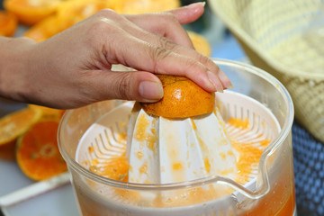 orange fruit squeezed with woman hand in juicer machine