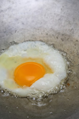 cooking fried egg in hot pan with oil