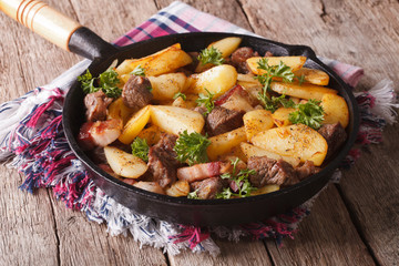 country fried potatoes with meat and bacon in a pan closeup. horizontal
