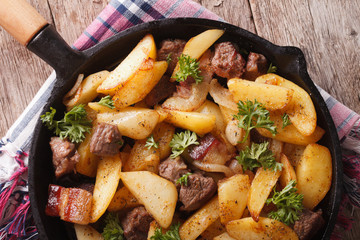 fried potatoes with meat and bacon in a pan close-up. Horizontal top view 
