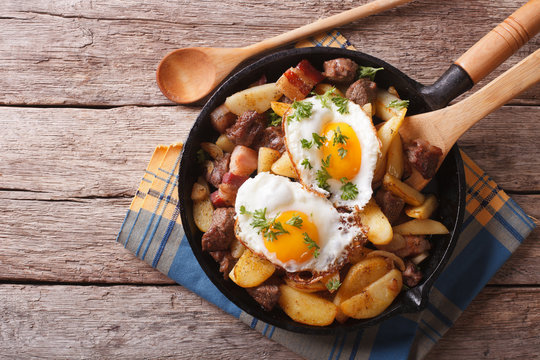  fried potatoes with meat, bacon and eggs in a pan. horizontal top view
