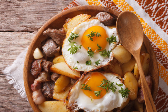 fried potatoes with meat and eggs close-up in a bowl. horizontal top view
