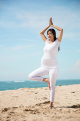 Fototapeta na wymiar Pregnant asian woman doing yoga in the sea shore
