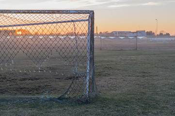 Abandoned soccer field and old rusty goals on sunset, nostalgia concept