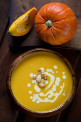 Above view of fresh pumpkin cream-soup in a wooden bowl, closeup