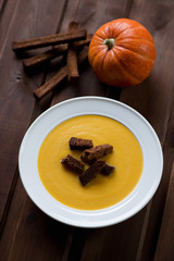 Pumpkin cream-soup with croutons on a dark wooden background