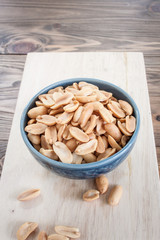 Salted peanuts blue ceramic bowl on a wooden floor