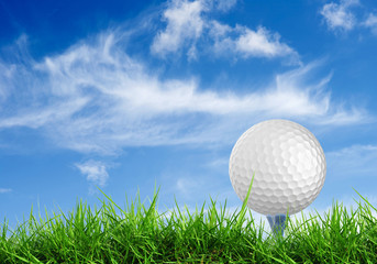 close up golf ball on tee with grass field blue sky background