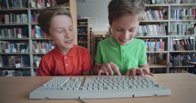 Twin brothers arguing while typing on computer keyboard at school 