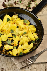Roasted potato in a frying pan on wooden table