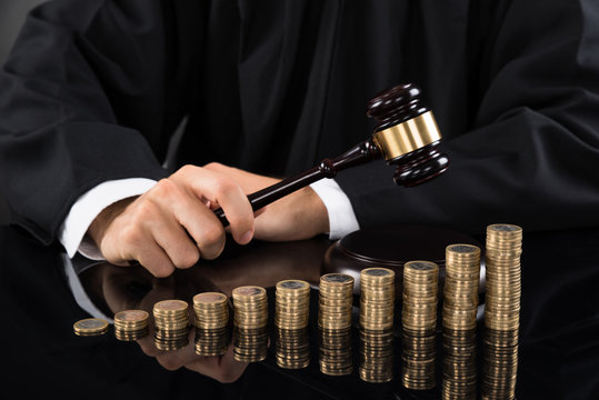 Judge Hitting Gavel In Front Of Coins