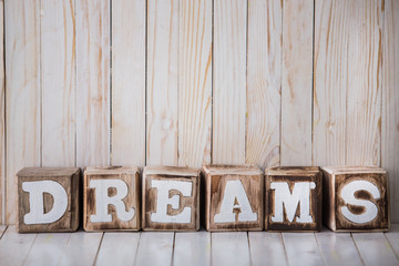 DREAMS sign made of wooden blocks on wooden background