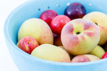 Juicy peaches and apricots in wooden bowl