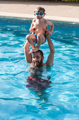 Niño jugando con su padre en la piscina