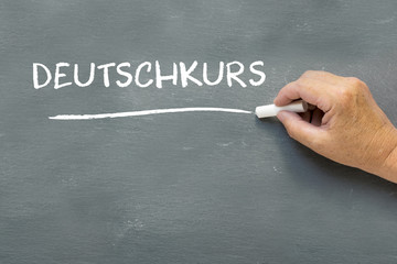 Hand on a chalkboard with the German word Deutschkurs (German co