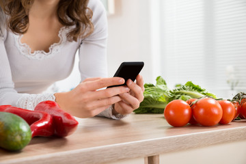Woman Using Mobile Phone In Kitchen