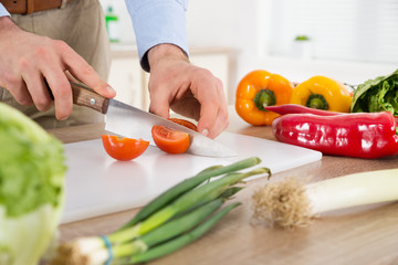 Male Hands Cutting Tomato At Countertop