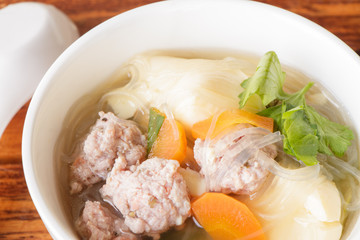 clear soup with pork in white plate put on wooden background, Thai cuisine.