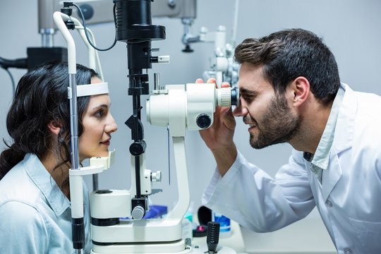  Optician examining womans eyes through slit lamp