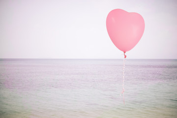 Grunge pink balloon over sea sky background with retro filter ef