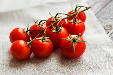 Cherry tomatoes on a wooden surface and homespun cloth with natural light.