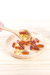 Closeup soft gelatin supplement fish oil capsule on wooden