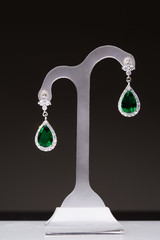 earrings with green stones on a stand