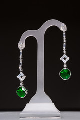 earrings with green stones on a stand