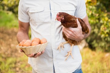  Happy farmer holding chicken and eggs