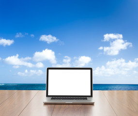 Laptop computer on wood table with sea background