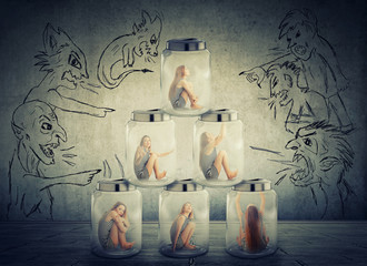 lonely woman sitting in a pile of glass jars surrounded by angry negative evil men
