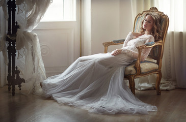 Model Bride in the studio sitting on a chair in the sunshine.