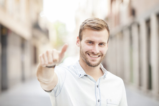 young man smiling with thumbs up, outdoor